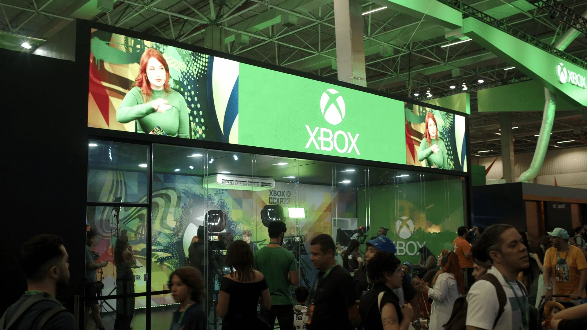 Estande da Xbox na CCXP23, com painéis de LED verdes e o público à frente.