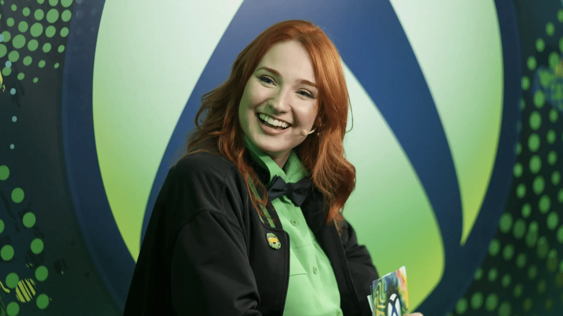 Apresentadora sorrindo diante do símbolo da Xbox.
