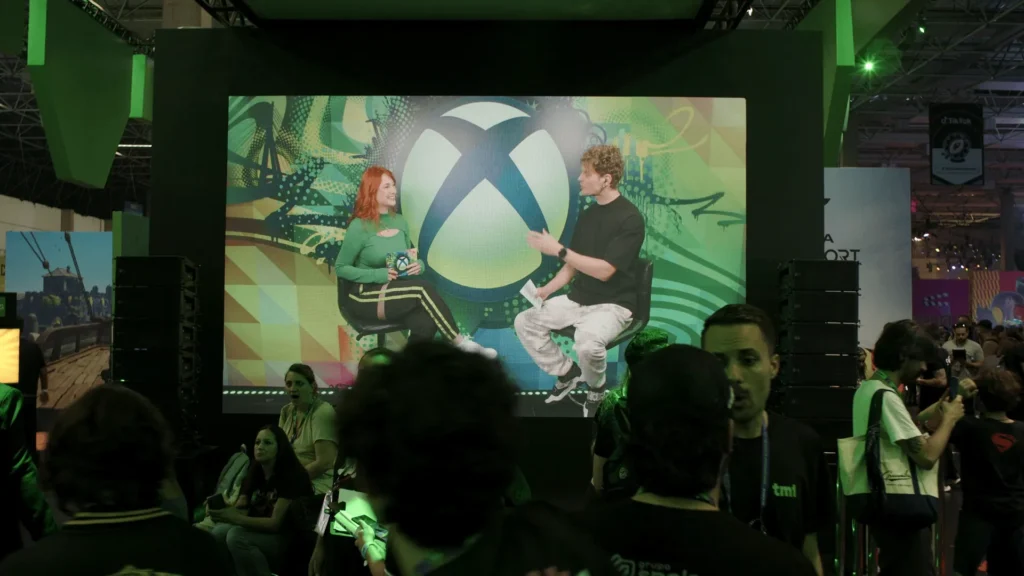 Palco do Glass Studio com o telão do símbolo da Xbox e a plateia à frente.