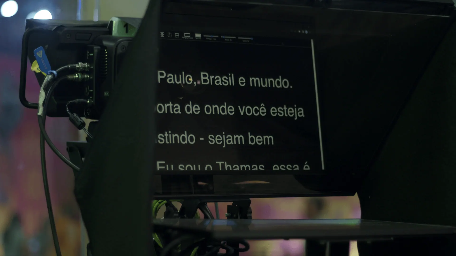 Teleprompter com o roteiro da transmissão, ao lado de uma câmera.